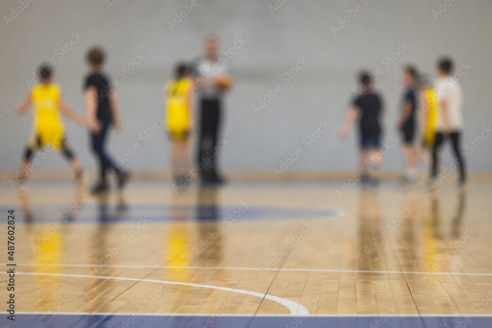 View of basketball court hall indoor venue with junior teenage school team playing in the background, basketball match game on arena stadium, team is blurred with copy space View of basketball court hall indoor venue with junior teenage school team playing in the background, basketball match game on arena stadium, team is blurred with copy space