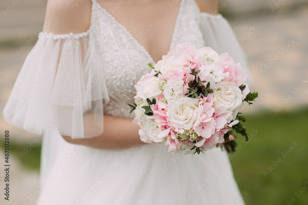 A bride in a summer meadow holds a bouquet of flowers in her hands 400 A bride in a summer meadow holds a bouquet of flowers in her hands 400
