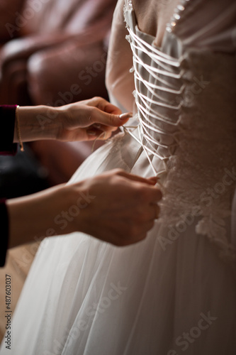 The hands of a friend tie the laces on the brides dress 4044.