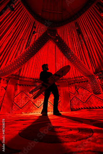 Man with snowboard inside Yurt nomadic house with red lights photo