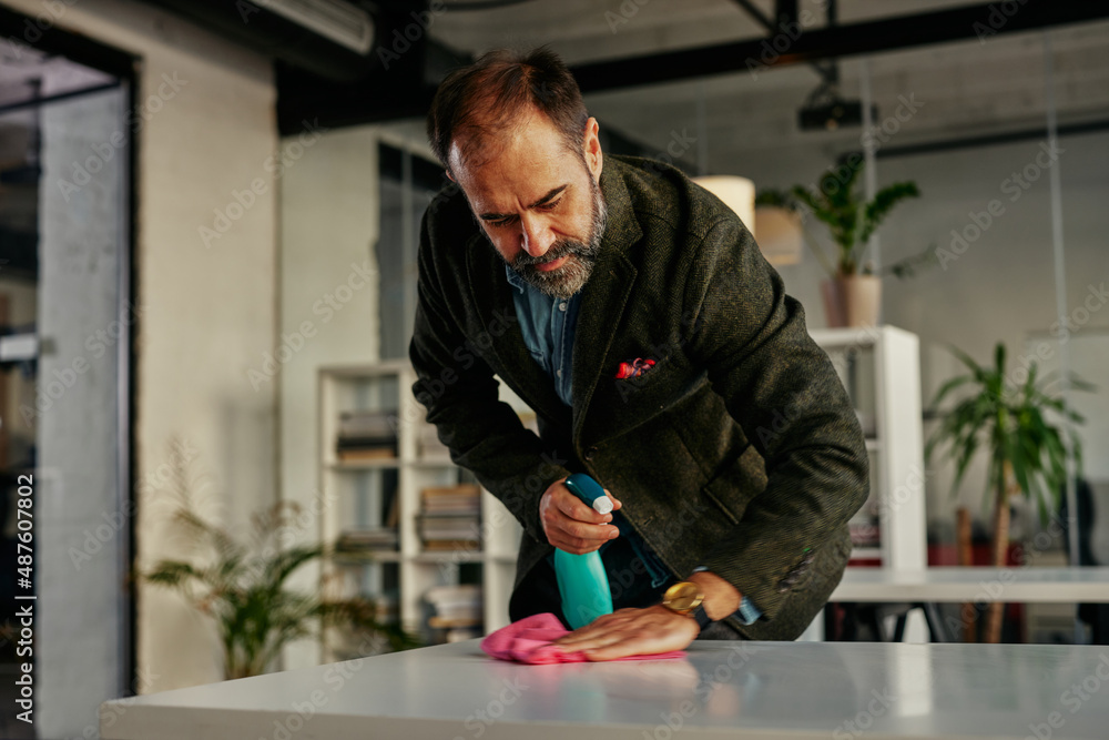 Obraz premium Businessman disinfecting desk at office