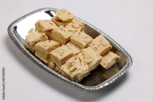 Shompapri Soan papdi cube cut flaky sweet made from flower ghee sugar on silver metal tray plate photo