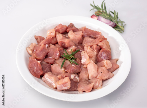 Diced meat on a white plate, isolated, close up. Raw poultry, pork meat in cubes, on a white background.