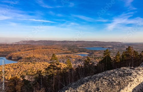 Autumn landscape from the top of a mountain with a lake, trees, mountains and sky