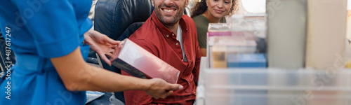 Fotografia Smiling stewardess offering products or gifts to buy to passengers on aircraft