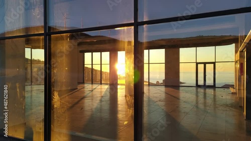 Retail space for lease. Interior of an office or business property for rent or sale. Setting sun shining through windows of an empty floor of real estate, sky reflecting in the glass.