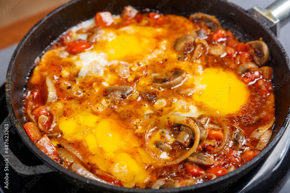Shakshuka with herbs in a frying pan on a gray background.close-up. Shakshuka with herbs in a frying pan on a gray background.close-up.