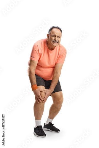 Full length portrait of a mature man in sportswear holding his painful knee