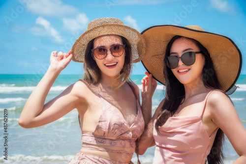 Portrait of two Happy traveller woman wearing straw in dress enjoys her during summer tropical beach vacation. Holiday and summer travel concept