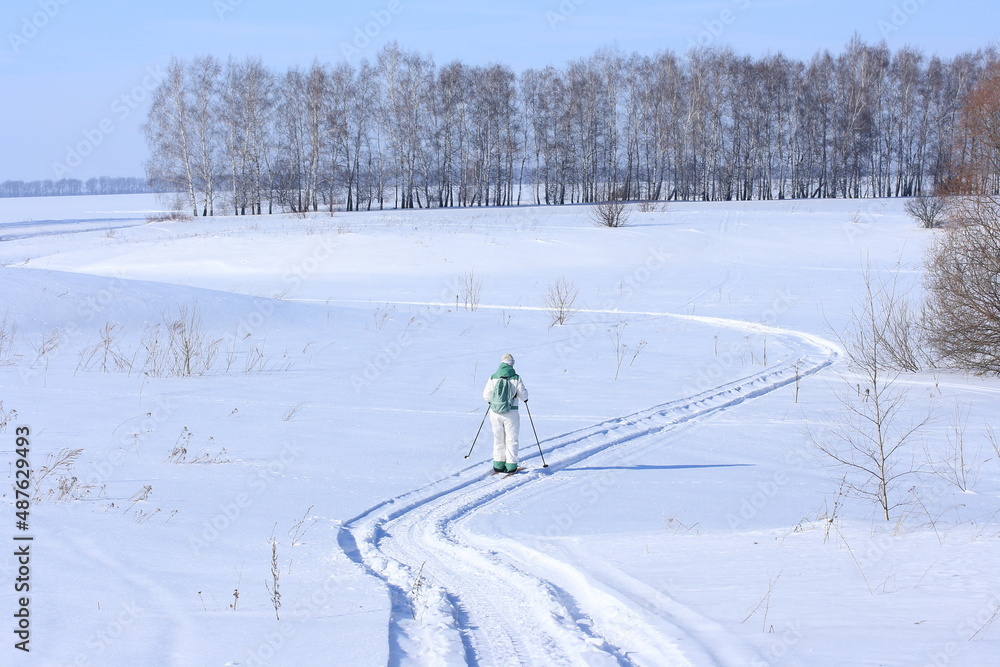 A skier rides on a snowmobile trail on a sunny winter day A skier rides on a snowmobile trail on a sunny winter day
