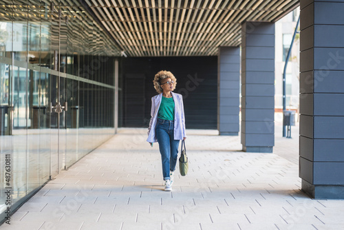 Confident black business woman walking in office district smiling empowered African American female executive enjoying successful corporate career