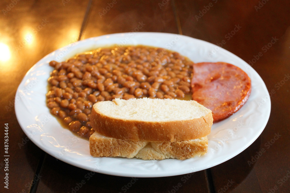 Close-up of a plate of baked beans with ham and a slice of bread. Close-up of a plate of baked beans with ham and a slice of bread.