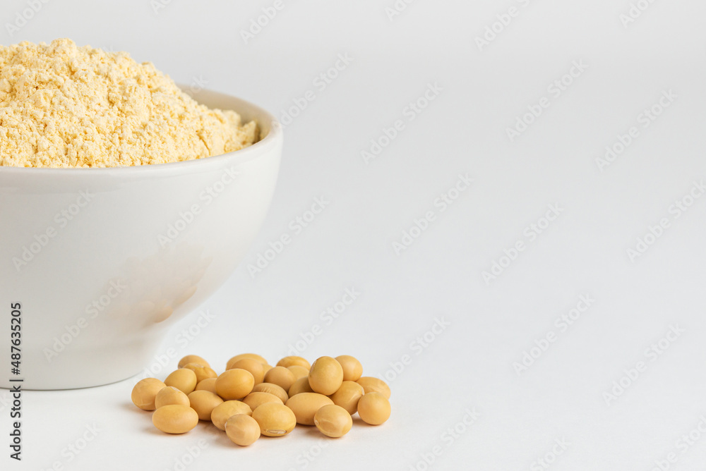 Fragment of white ceramic bowl with soy flour and soybeans on a white background with copy space Fragment of white ceramic bowl with soy flour and soybeans on a white background with copy space