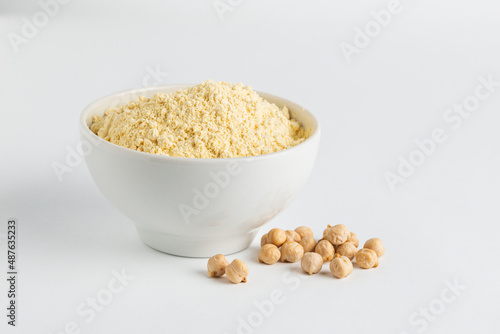 Chickpea flour in white ceramic bowl and chickpeas beans on a white background clouse up