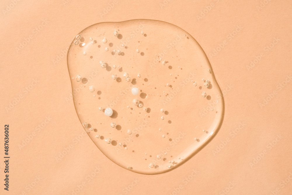 Drop of transparent cosmetic textured gel background with bubbles on beige glass. Copy space. Bath gel background Drop of transparent cosmetic textured gel background with bubbles on beige glass. Copy space. Bath gel background