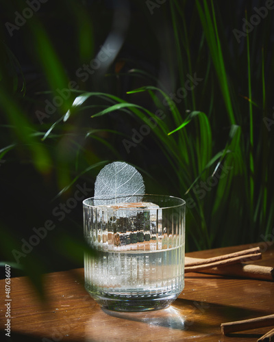 beautiful small cocktail with ice cube and leaf in a bar table