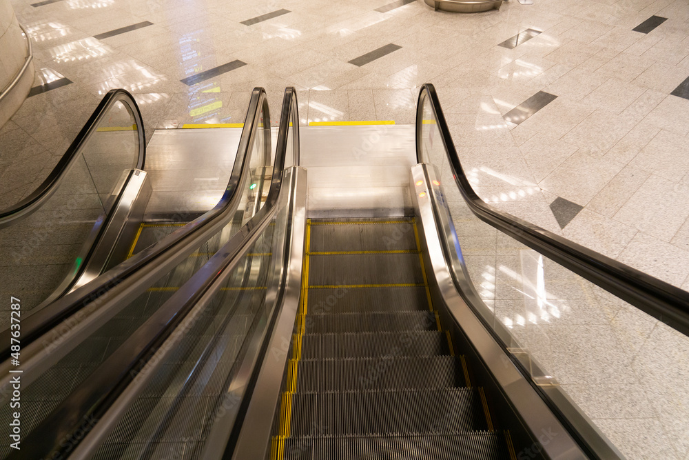 Fototapeta premium Top view of the escalator. Empty metro station. The escalator stairs lead down.