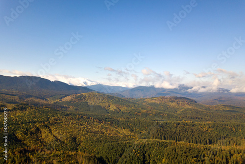 Fototapeta Naklejka Na Ścianę i Meble -  Aerial view of majestic mountains covered with green spruce forest and high snowy peaks.
