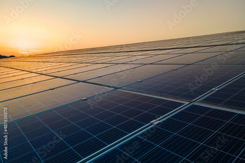 Blue photovoltaic solar panels mounted on building roof for producing clean ecological electricity at sunset. Production of renewable energy concept
