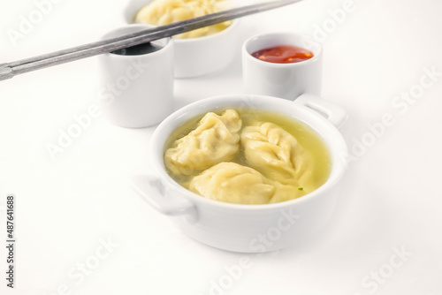 Steamed dumplings and soy sauce. asian dumplings Gyoza potstickers in white ceramic plate served with chopsticks over linen table cloth. Asian dinner.