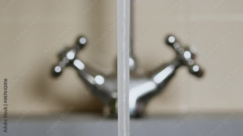 Opening and closing water flow tap in kitchen. Turn on faucet valve, water start running to sink. Strong flow pouring down. Common bathroom equipment. Slow motion shot, close up