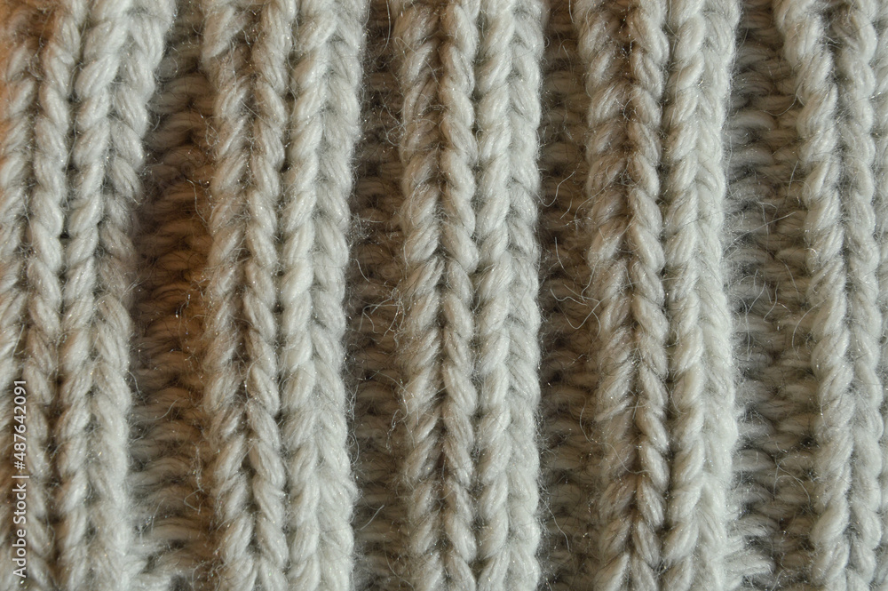 large knitting needles. texture with gray woolen threads. background for the design. the pattern is in braids.