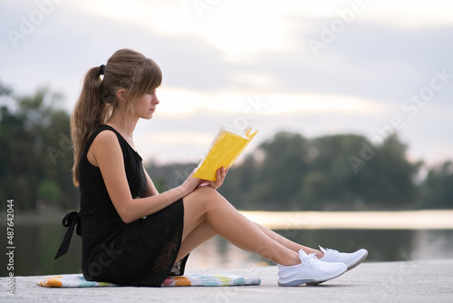 Young woman resting in summer park reading a book. Education and sudy concept photo