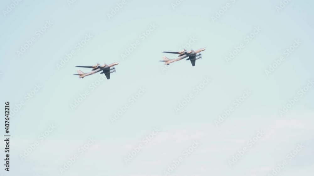 Two Russian military Tu-95 missile-carrying turboprop bombers fly in the blue sky. Close-up of propeller-driven aircraft. Two Russian military Tu-95 missile-carrying turboprop bombers fly in the blue sky. Close-up of propeller-driven aircraft.