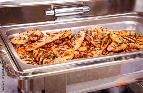 Grilled barbecue chicken breast in a large silver catering tray at a local outdoor event