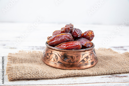 Plate of dates on a white wooden background. Dried date fruits or kurma, ramadan (ramadan) food. photo