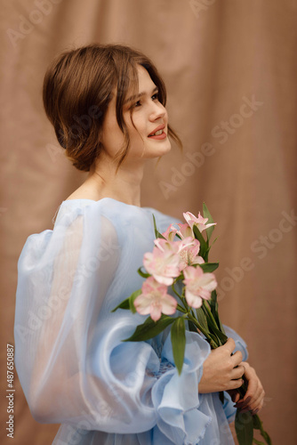 a girl in a blue dress with flowers in her hands