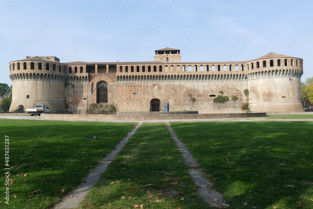 Sforza Castle in Imola, the main building with ravines sorrouded by circular bastions and a moat and a green lawn in front