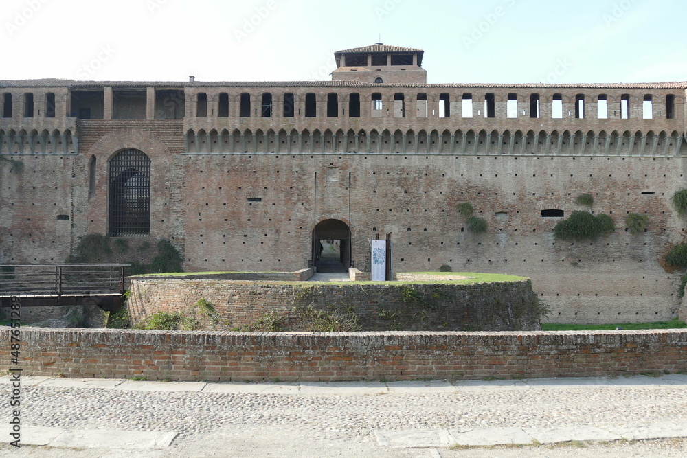 Sforza Castle in Imola, the main building with ravines sorrouded by circular bastions and a moat and a green lawn in front