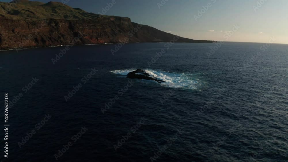 Aerial arc shot around rock in ocean on backdrop of Verodal beach Aerial arc shot around rock in ocean on backdrop of Verodal beach