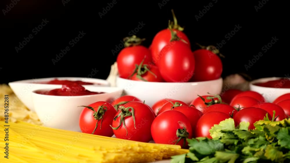 Ingredients of italian or mediterranean cuisine: Pasta spaghetti farfalle, spices, garlic, ketchup, salt, pepper, tomato sauce and fresh tomatoes on kitchen board. Italian food slow motion rotating Ingredients of italian or mediterranean cuisine: Pasta spaghetti farfalle, spices, garlic, ketchup, salt, pepper, tomato sauce and fresh tomatoes on kitchen board. Italian food slow motion rotating
