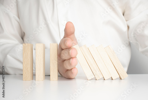 The concept of stopping the crisis. Hand holds wooden blocks on a blue background. Close up.