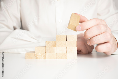 Hand stacking wooden blocks for in shape of staircase. Business development, strategy concept. Building success foundation