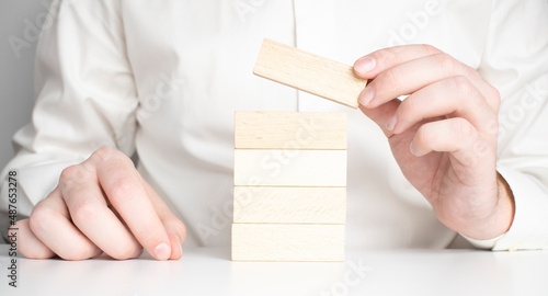 Man hand put wooden blocks in the shape of a staircase isolated on white background with copy space. Concept of building success foundation