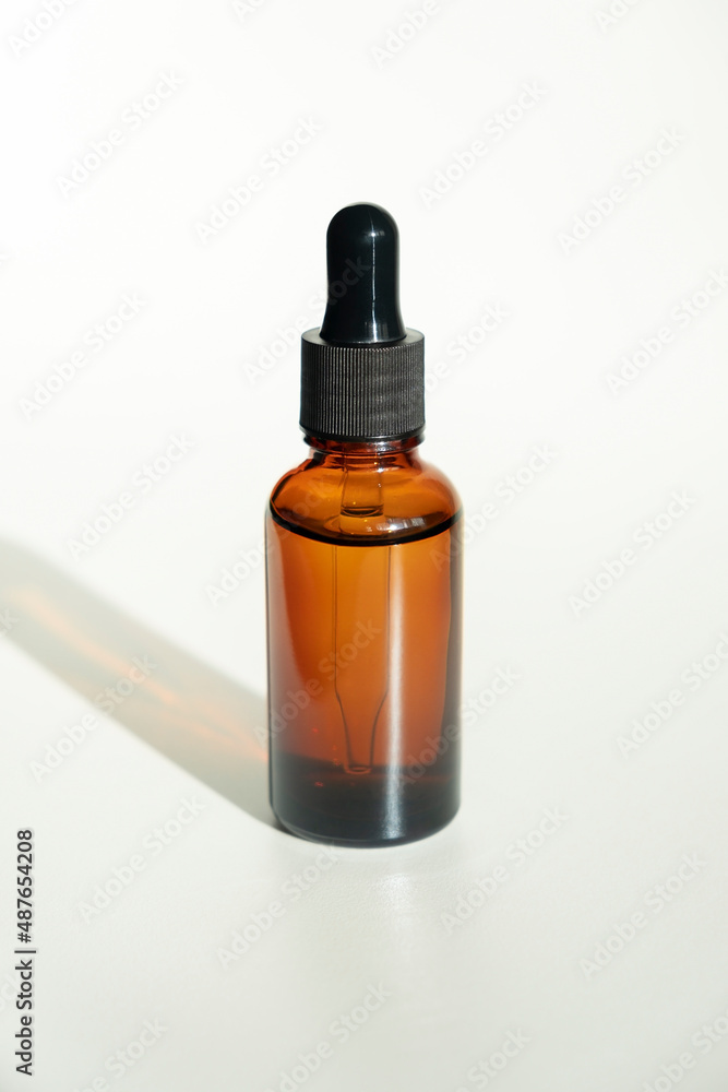 Bottle with dropper pipette with serum or essential oil. White background with daylight. Skincare products , natural cosmetic. Beauty concept for face and body care Bottle with dropper pipette with serum or essential oil. White background with daylight. Skincare products , natural cosmetic. Beauty concept for face and body care