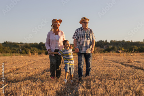 Grandparents with the grandson. They're playing on the meadow and joying in sunset. 