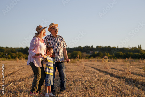 Grandparents with the grandson. They re playing on the meadow and joying in sunset. 