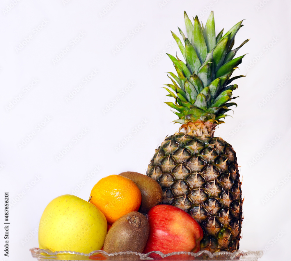 Apples tangerines kiwi and pineapple in the background on a white background Apples tangerines kiwi and pineapple in the background on a white background