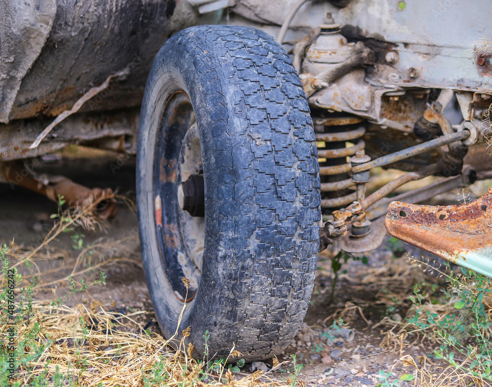 The front suspension and the hub of an abandoned rusty retro car in a web. The front suspension and the hub of an abandoned rusty retro car in a web.