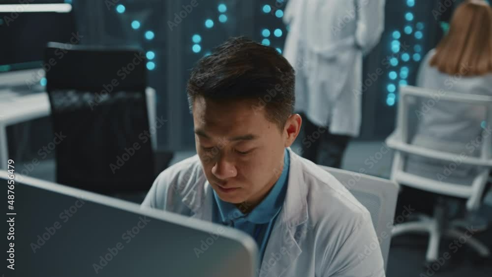 Data center. Asian software developer IT technologist using desktop computer conducting research cooperating. Multiple monitors. Server racks. Technology and science. Data center. Asian software developer IT technologist using desktop computer conducting research cooperating. Multiple monitors. Server racks. Technology and science.