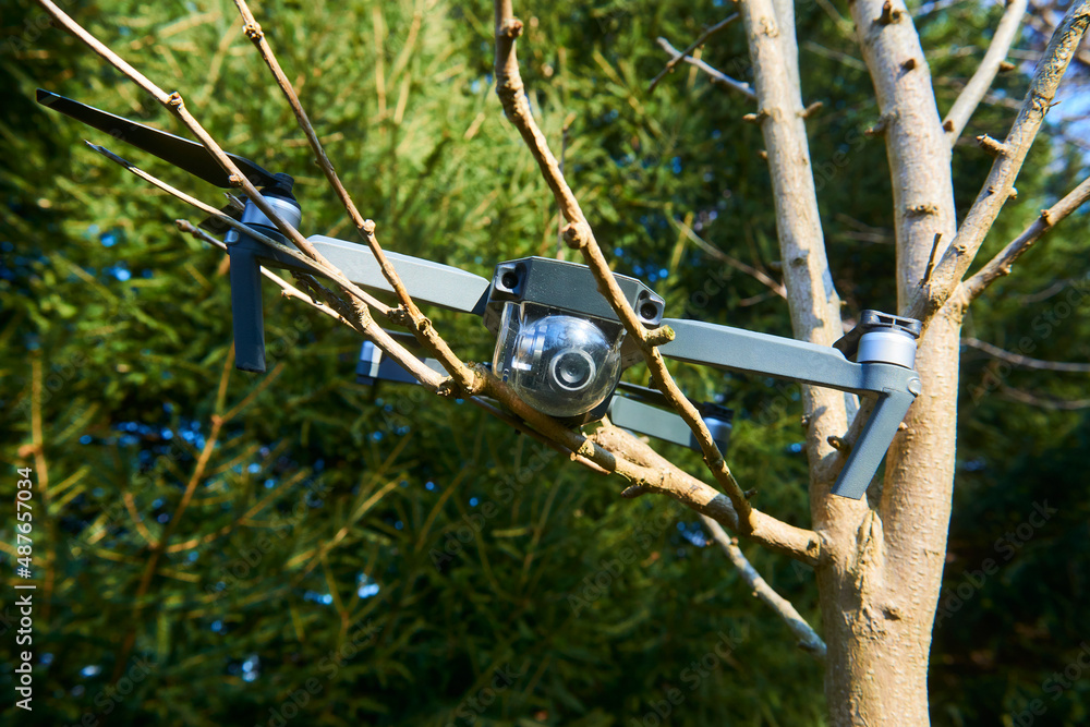 Drone quadcopter accident scene. UAV Quadrocopter crashed on tree in forest. Drone quadcopter accident scene. Destroyed expensive drone hanging in the branches of spruce Drone quadcopter accident scene. UAV Quadrocopter crashed on tree in forest. Drone quadcopter accident scene. Destroyed expensive drone hanging in the branches of spruce