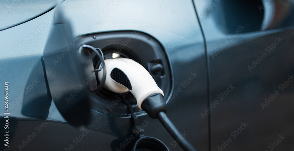 EV car on charging station. Close-up of plug. Panoramic banner. EV car on charging station. Close-up of plug. Panoramic banner.