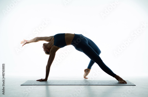 Flexible young fit girl practice yoga perform Wild Thing Pose for stretching, wellness. Beautiful ballerina training