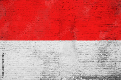 Full frame photo of a weathered flag of Indonesia painted on a plastered brick wall.