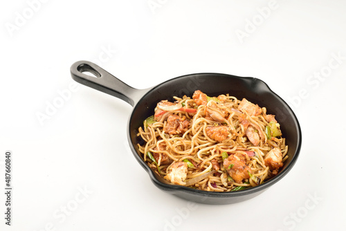 spicy chicken noodles in skillet pan on white background