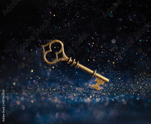 Obraz na plátně Single golden skeleton key surrounded by sparkling lights